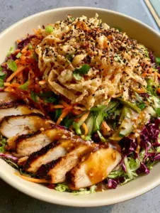 Close-up of Wonton Salad showing shredded green cabbage, purple radicchio, and charred chicken edges. (Wonton Salad)