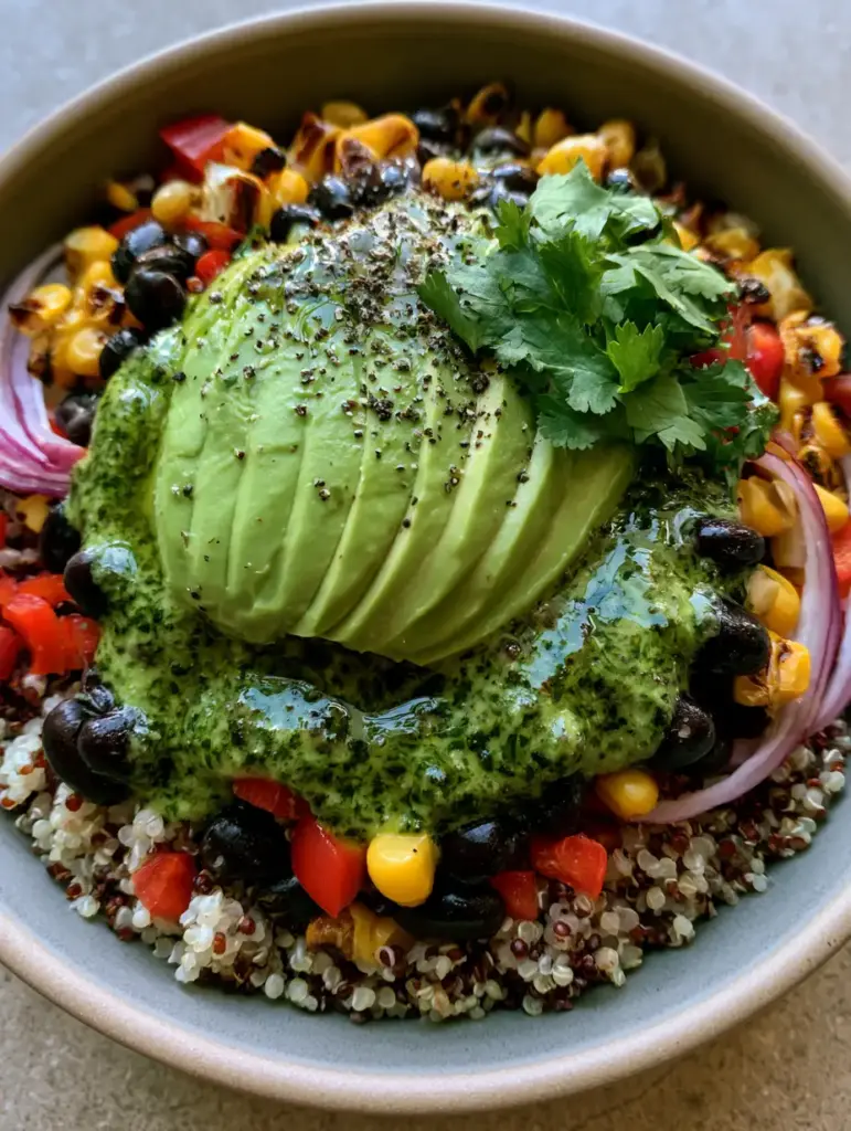 A matte ceramic bowl filled with Southwest quinoa salad topped with a thick cilantro lime dressing and jagged herbs.