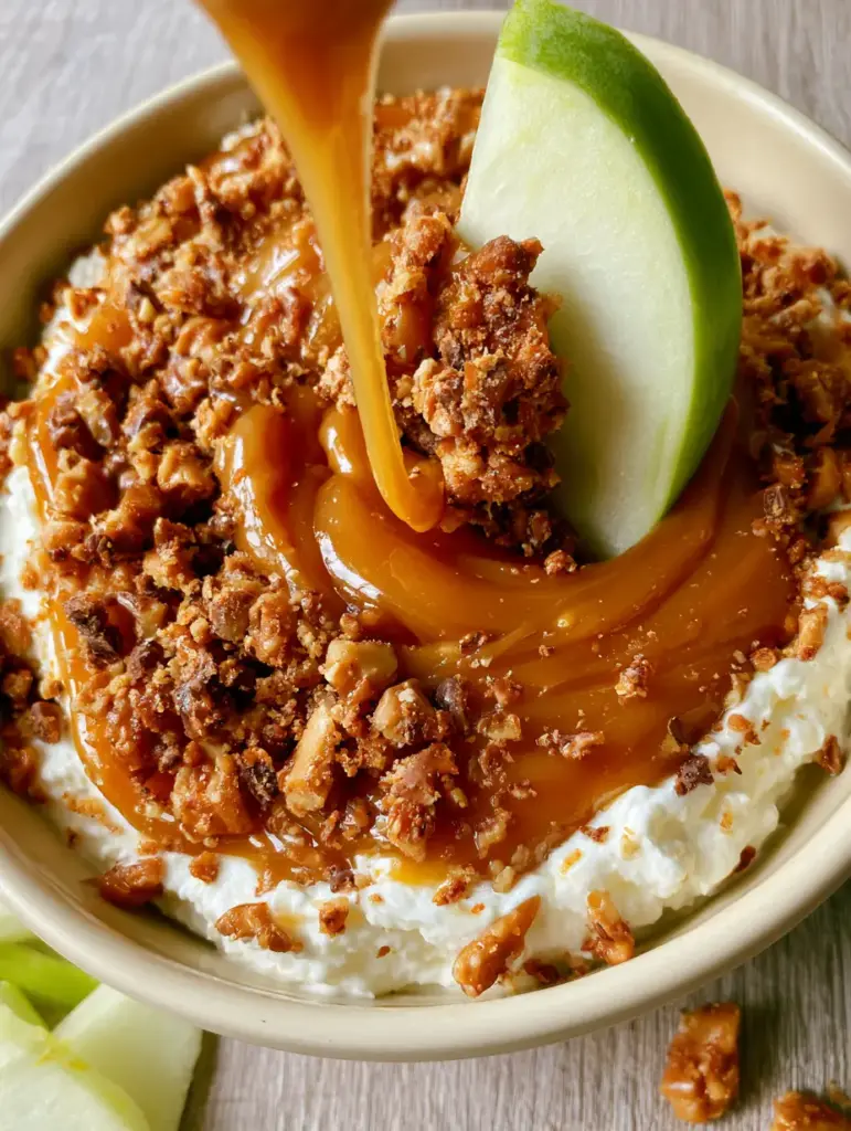 Detailed view of a Granny Smith apple slice dipping into a Caramel Apple Dip bowl, pulling up a ribbon of caramel and toffee shards.