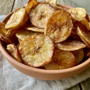 Macro close-up of paper-thin Air Fryer Banana Chips showing rippled texture, visible fiber patterns, and sparkling flaky sea salt crystals.