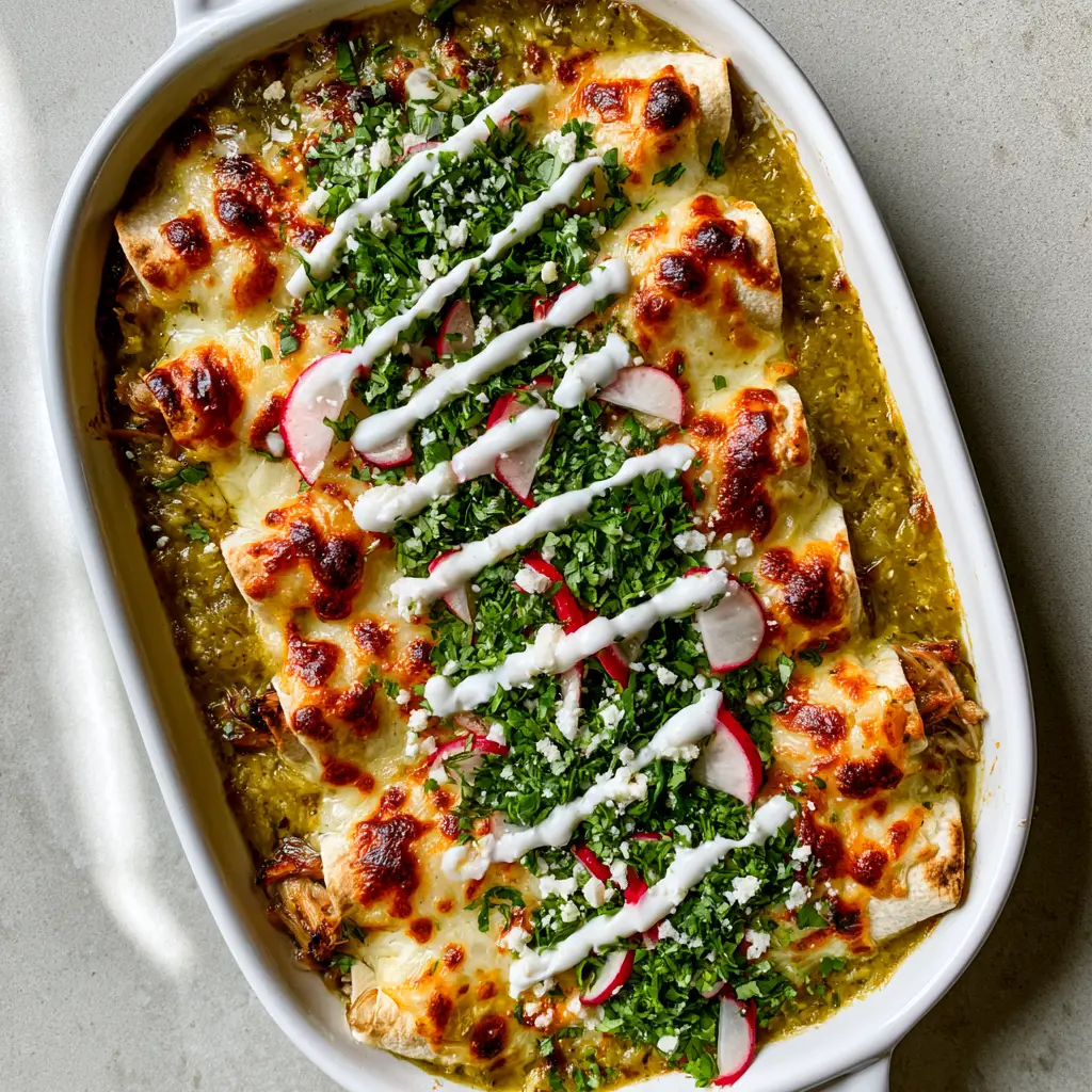 Detailed close-up of pulled pork enchiladas verde garnished with cilantro, radish slices, and Mexican crema zig-zags.