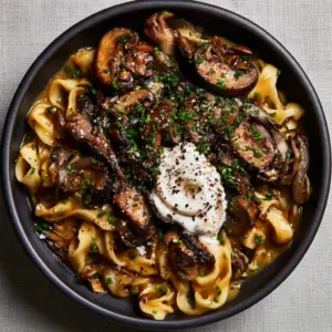 Top-down macro shot of mushroom stroganoff recipe showing glossy sauce and caramelized mushroom edges.